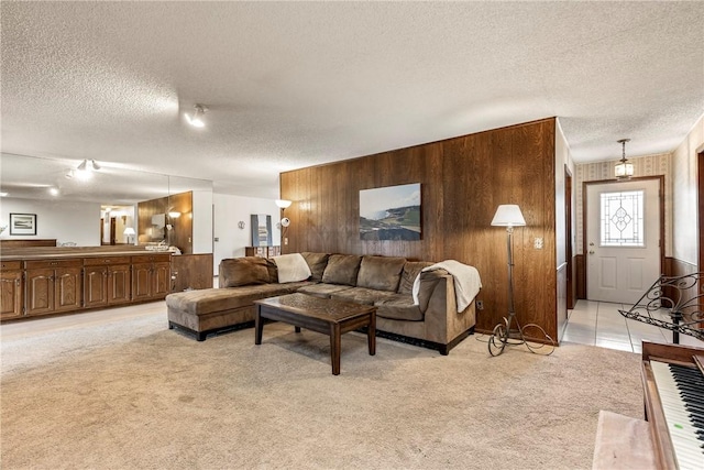 living area with light carpet, wood walls, and a textured ceiling