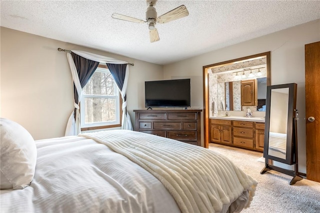 bedroom with a ceiling fan, light colored carpet, connected bathroom, and a textured ceiling