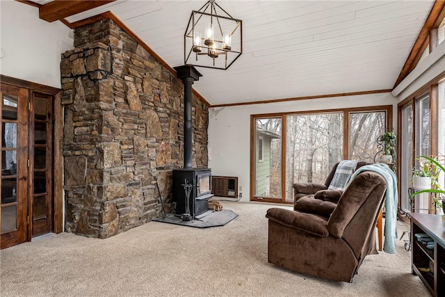 living area featuring crown molding, an inviting chandelier, a wood stove, carpet flooring, and high vaulted ceiling