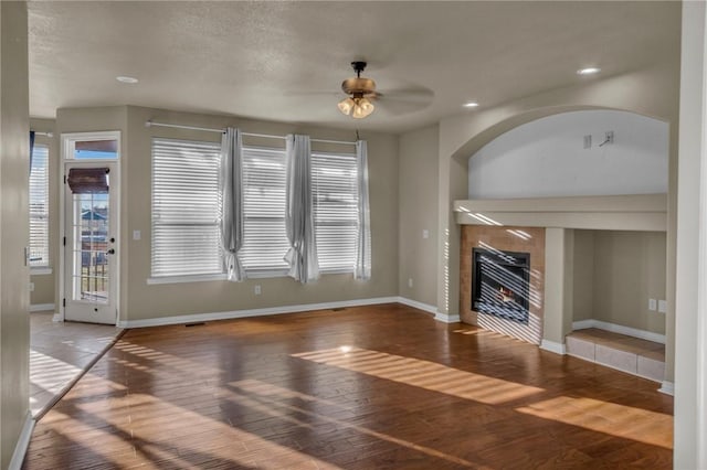 unfurnished living room with hardwood / wood-style flooring, recessed lighting, a ceiling fan, baseboards, and a tiled fireplace