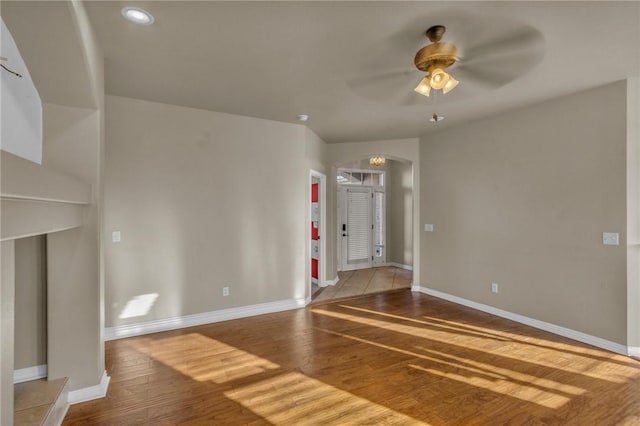 unfurnished living room with wood finished floors, a ceiling fan, and baseboards