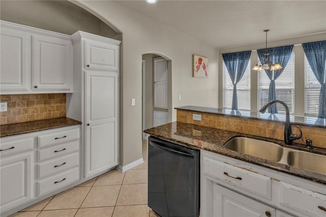 kitchen with light tile patterned floors, black dishwasher, arched walkways, a sink, and backsplash