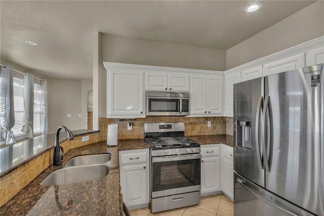 kitchen with stainless steel appliances, white cabinets, a sink, and decorative backsplash