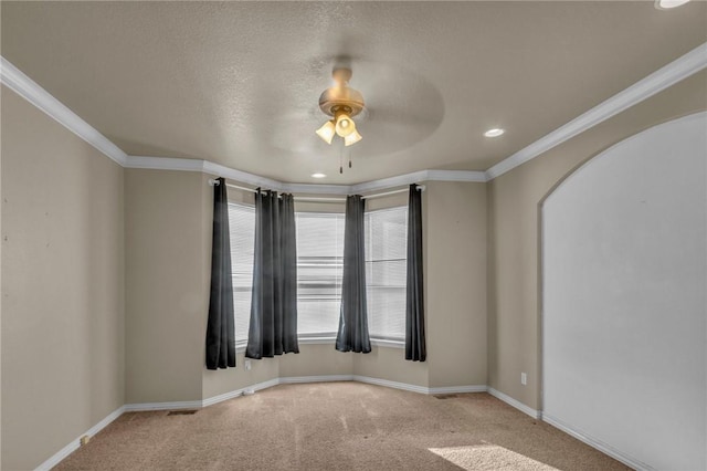 spare room with carpet, crown molding, arched walkways, and baseboards