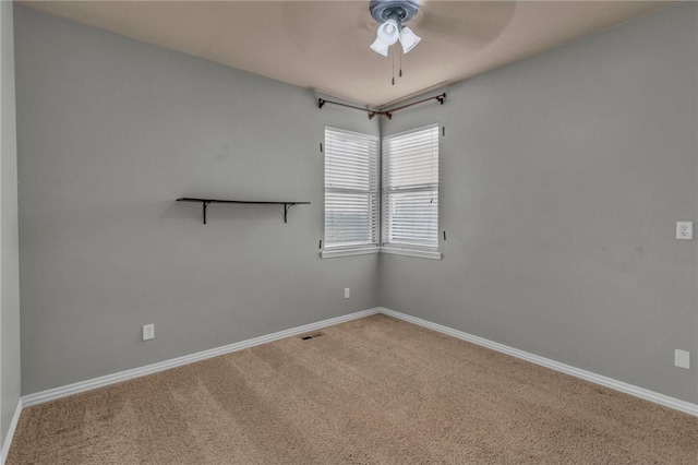 empty room featuring carpet floors, visible vents, ceiling fan, and baseboards