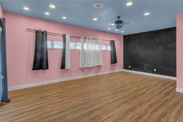 spare room with an accent wall, baseboards, wood finished floors, and recessed lighting