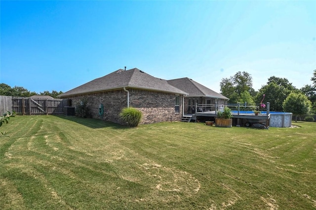 view of side of property featuring brick siding, an outdoor pool, fence, and a lawn