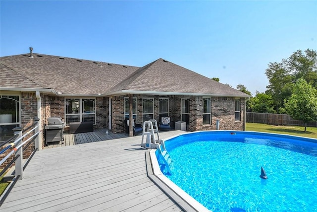 view of swimming pool featuring grilling area, a wooden deck, a fenced in pool, and fence