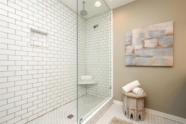 full bathroom featuring tile patterned flooring, a tile shower, and baseboards