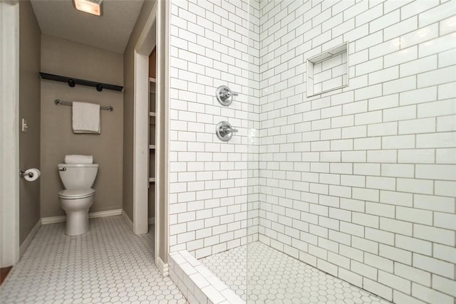 full bathroom featuring a stall shower, baseboards, toilet, and tile patterned floors