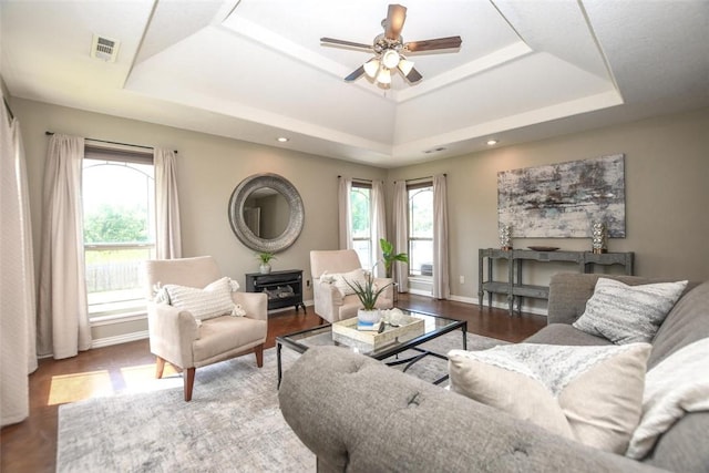 living area with visible vents, a raised ceiling, and a wealth of natural light