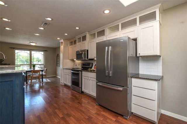 kitchen with stainless steel appliances, dark wood-style flooring, visible vents, decorative backsplash, and glass insert cabinets