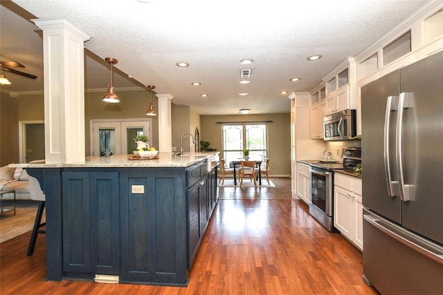 kitchen with stainless steel appliances, a breakfast bar area, a sink, and ornate columns