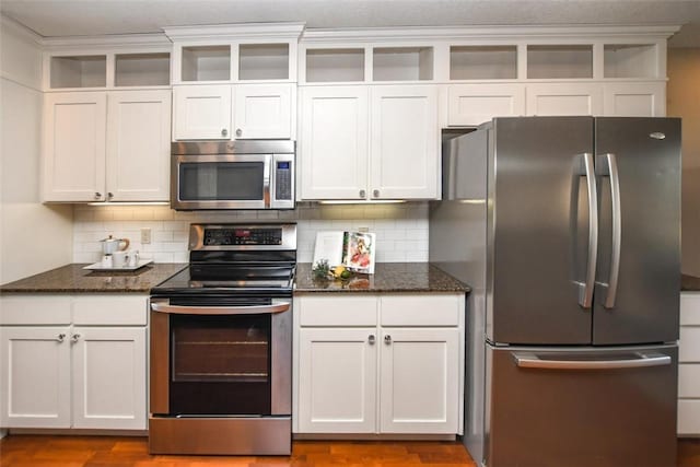 kitchen with open shelves, backsplash, stainless steel appliances, and dark stone countertops