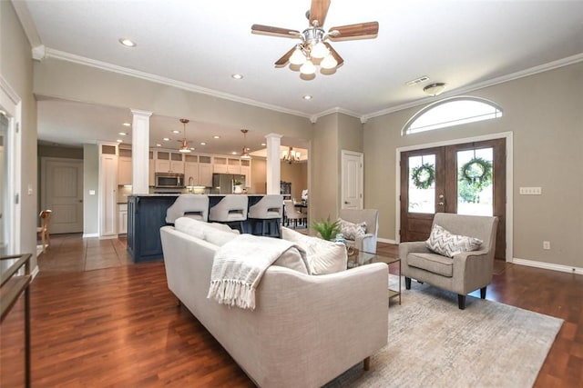 living area with dark wood-style floors, ornate columns, ornamental molding, ceiling fan, and baseboards