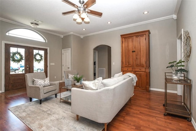 living room with arched walkways, dark wood-style flooring, visible vents, baseboards, and ornamental molding