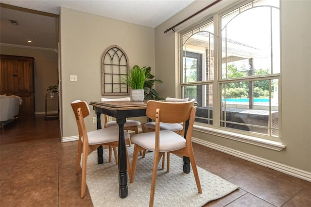 tiled dining room with ornamental molding and baseboards