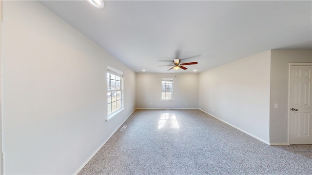 unfurnished room with ceiling fan, light colored carpet, visible vents, and baseboards