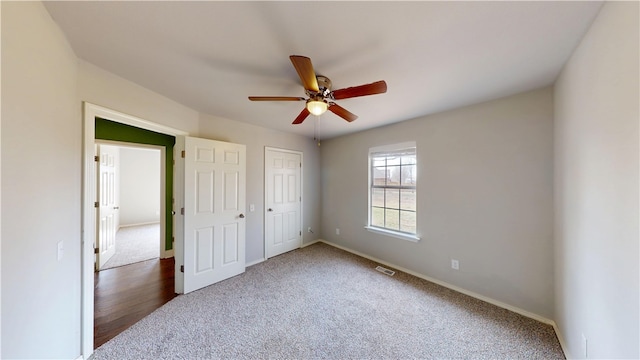 unfurnished bedroom with baseboards, visible vents, ceiling fan, and carpet flooring