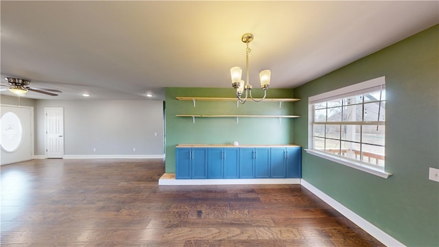 unfurnished room featuring baseboards, dark wood-style flooring, and ceiling fan with notable chandelier