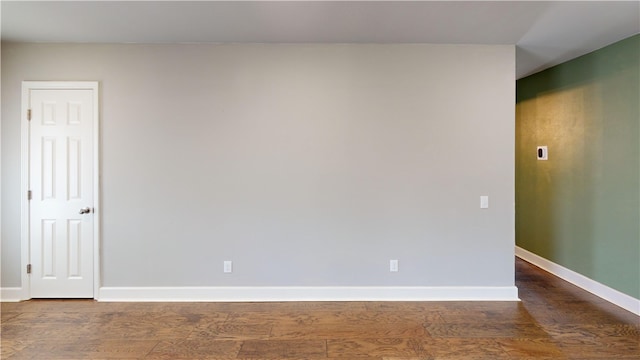 spare room with baseboards and wood finished floors