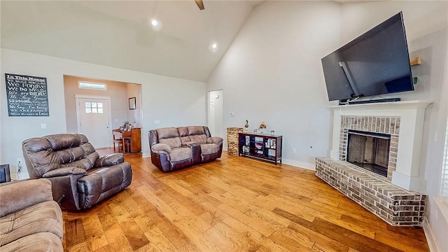 living room with light wood finished floors, baseboards, a fireplace, and high vaulted ceiling