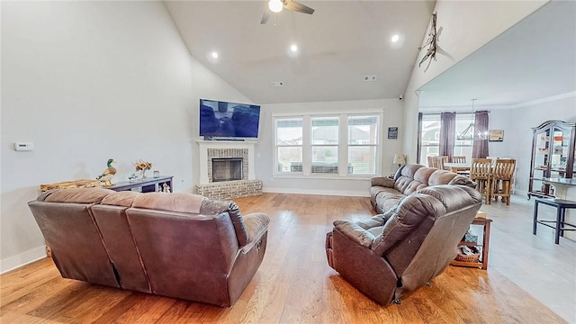 living area with light wood-style flooring, a fireplace, high vaulted ceiling, and a wealth of natural light