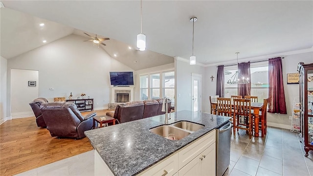 kitchen featuring a fireplace, a sink, white cabinets, dishwasher, and an island with sink