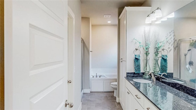 full bathroom featuring toilet, a stall shower, a bath, and vanity