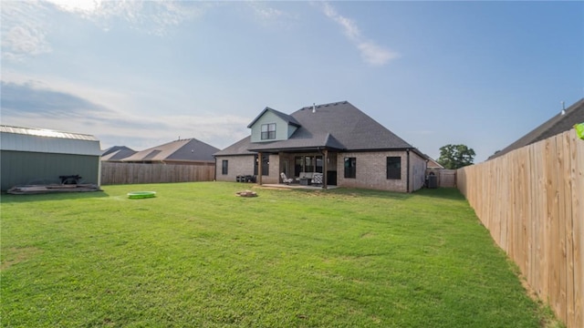 back of house with an outbuilding, brick siding, a yard, a patio, and a fenced backyard