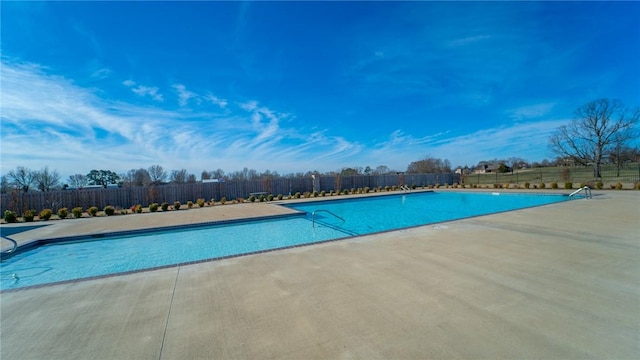 pool with a patio area and fence