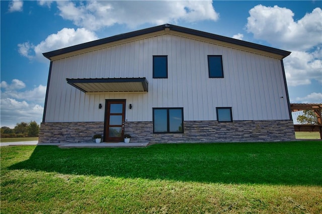 rear view of house featuring a yard and stone siding