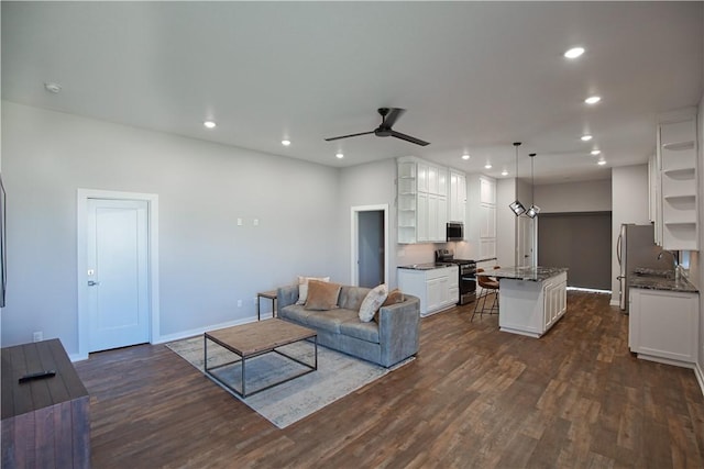 living room with baseboards, a ceiling fan, dark wood-type flooring, and recessed lighting