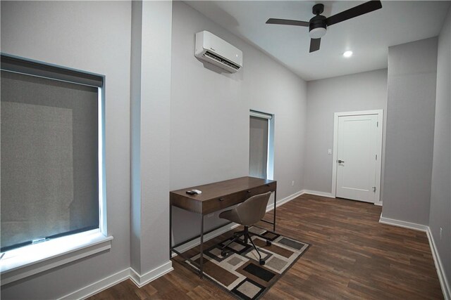 office area with a ceiling fan, dark wood-style flooring, a wall unit AC, and baseboards