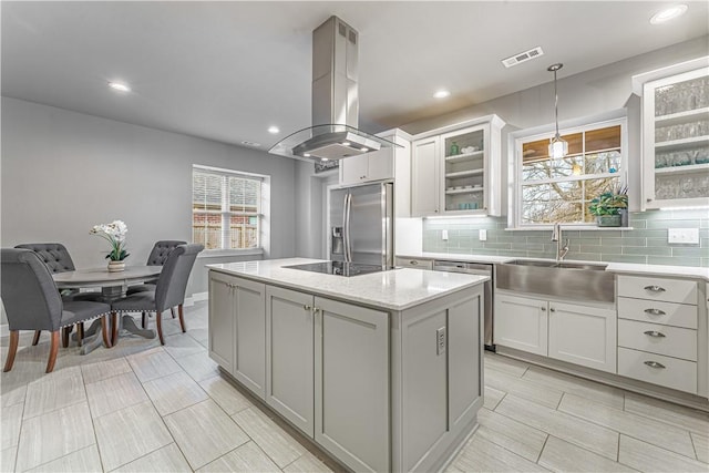 kitchen with island exhaust hood, a sink, a kitchen island, stainless steel fridge with ice dispenser, and black electric cooktop