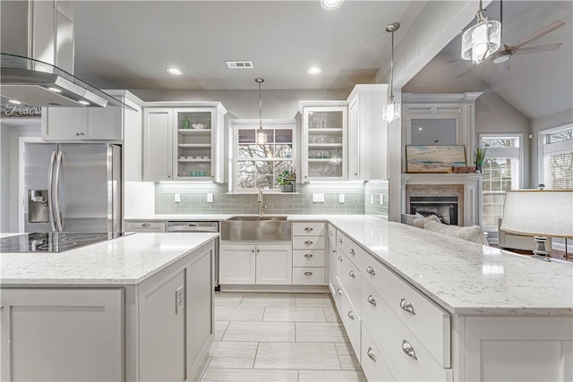 kitchen with visible vents, stainless steel fridge with ice dispenser, a peninsula, island range hood, and a sink