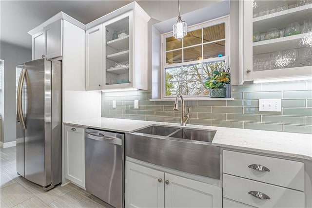 kitchen with a sink, light stone counters, backsplash, and stainless steel appliances