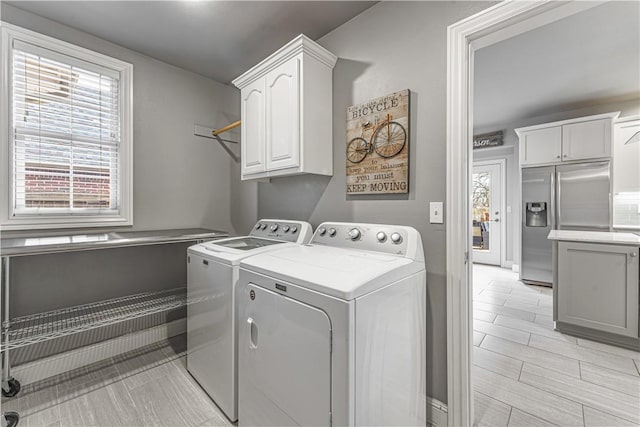 washroom featuring a wealth of natural light, cabinet space, and independent washer and dryer