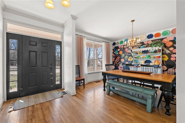 entrance foyer with baseboards, ornamental molding, wood finished floors, and an inviting chandelier