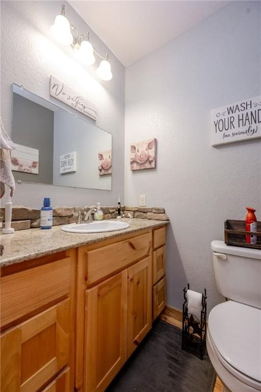 bathroom featuring toilet, wood finished floors, and vanity