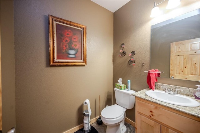 half bath featuring baseboards, a textured wall, vanity, and toilet