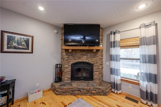 living area with baseboards, a fireplace, visible vents, and wood finished floors