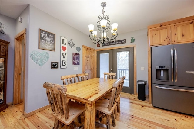 dining space featuring light wood-style floors, baseboards, a chandelier, and french doors