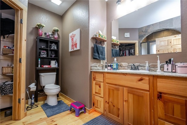 full bathroom featuring toilet, baseboards, wood finished floors, and vanity