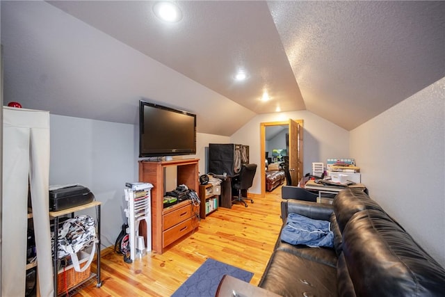 living room featuring vaulted ceiling, a textured ceiling, and light wood-type flooring