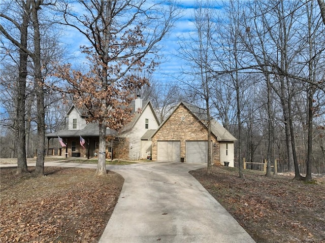 view of front of home with driveway, an attached garage, and a chimney