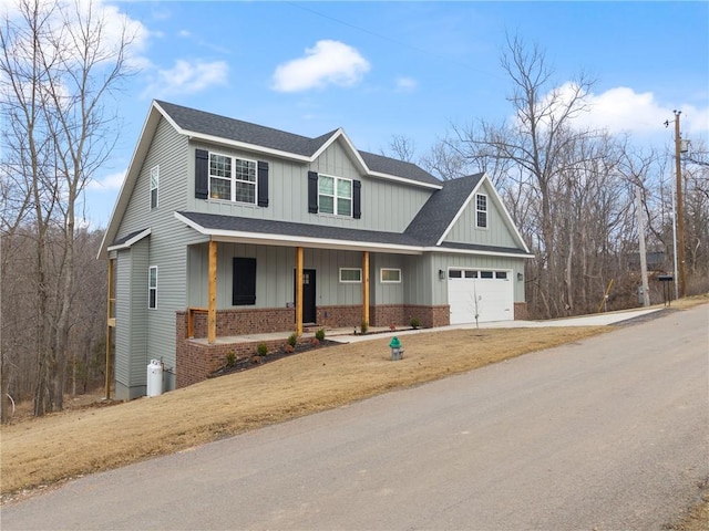 view of front of property featuring brick siding, a shingled roof, covered porch, a garage, and driveway