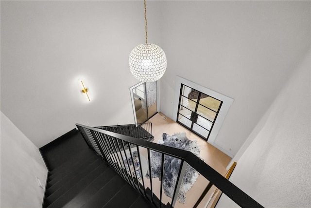 staircase featuring a high ceiling, baseboards, and wood finished floors