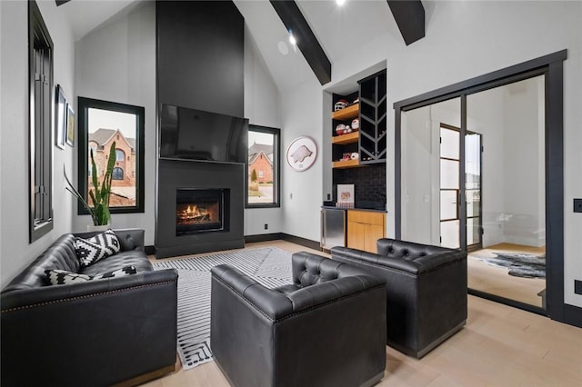 living room with high vaulted ceiling, a large fireplace, baseboards, light wood-style floors, and beam ceiling