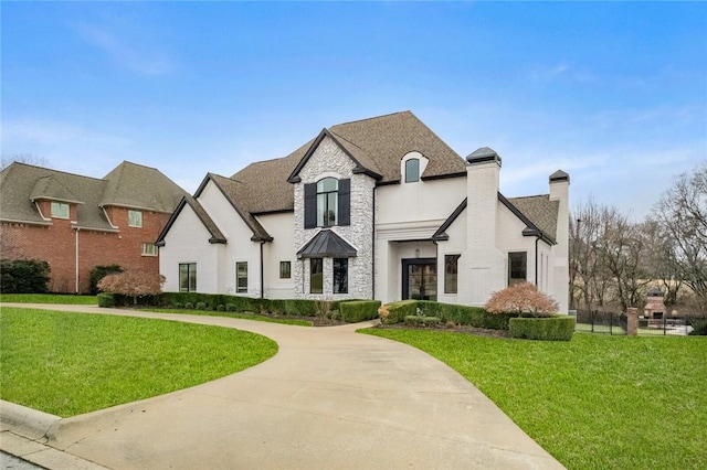 french country style house featuring a shingled roof and a front yard